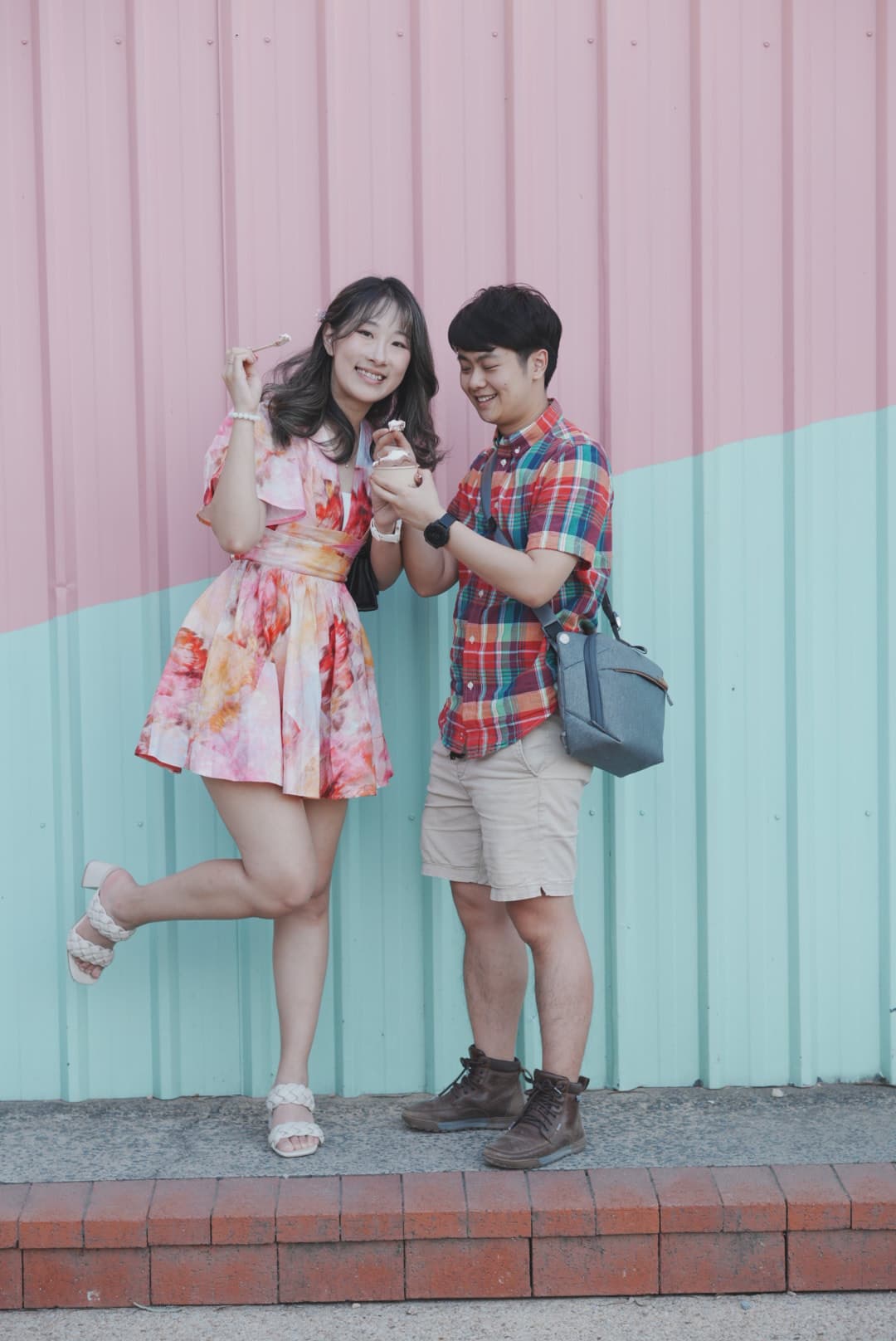 Thomas and Lylian enjoying icecream in front of pastel-coloured fences next to Pizza Teca.